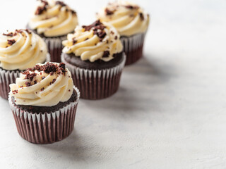 Chocolate muffins with cream and grated chocolate bars on a white background. Sweet food, holiday,...