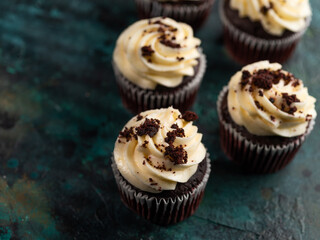 Chocolate cupcakes - brownies with cream, decorated with chocolate chips on a dark green background. Festive treat for birthday, anniversary, wedding. Sweet food.