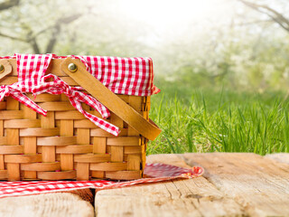 Summer vacation, picnic. On a wooden table, a beautifully decorated picnic basket against the background of beautiful summer nature, green grass. Rest, relaxation, picnic.