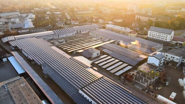 Aerial view of blue photovoltaic solar panels mounted on industrial building roof for producing green ecological electricity. Production of sustainable energy concept