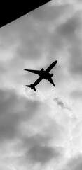 Commercial airplane flying above dramatic clouds in beautiful sunset light. flight travel transport airline background concept. Airplane shoot in black and white color