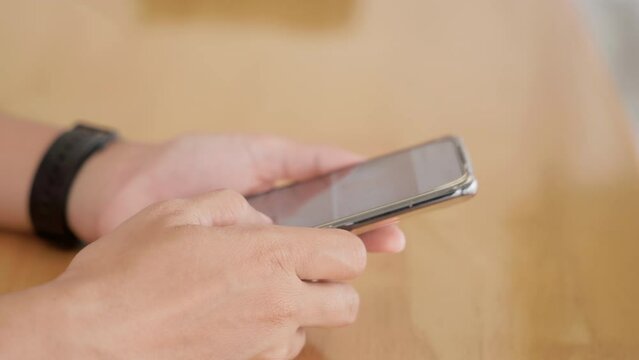 Hand of woman using application on smartphone she reading mail on social media at wooden teble, finger of happy female slide modern mobile phone screen, online internet searching