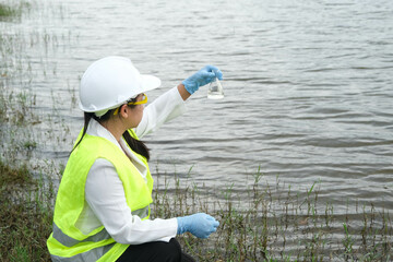 Female environmentalist in a glove takes a sample of lake water to survey and test for infection. Female researcher surveys contaminants in natural water bodies. Water and ecology concept. - obrazy, fototapety, plakaty