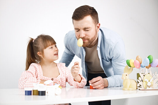 Girl with Down syndrome and her father playing with Easter colored eggs