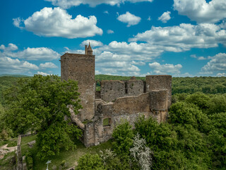 Fototapeta na wymiar Close up aerial view of the rectangular keep, ruined Gothic palace and circular defensive tower at Brancion castle and medieval village in Central France with cloudy blue sky