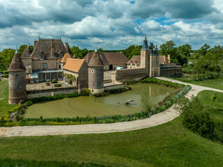 Fototapeta na wymiar Aerial view of Chteau de la Cour-en-Chapeau in Allier France constructed with black diamond-shaped bricks on a background of red bricks, palace, gate tower, corner towers and moat