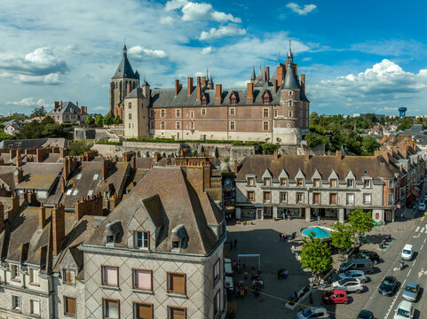 Aerial panoramic view of Gien castle in the Loire valley with a bridge stretching over the river, blue cloudy sky. Renaissance Chateau made of limestone and brick with decorative architecture