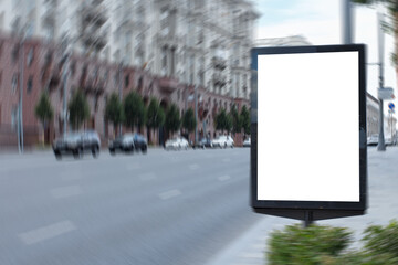 White blank vertical billboard in the blured city. Ancient architecture of the city. Mock-up.