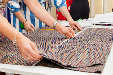 Two charming women fashion designers lay out the material and pattern for the new collection