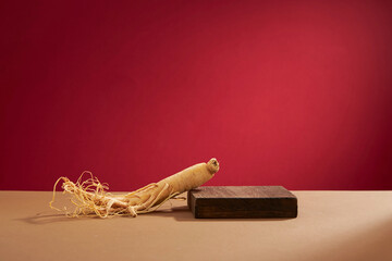 Front view of ginseng in wooden tray and red background  - obrazy, fototapety, plakaty
