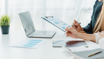 Two Asian female office workers working together with laptop at the white working desk in the comfortable meeting room.
