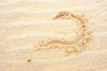 Fototapeta na wymiar Question mark drawn on the sea sand close-up from above.