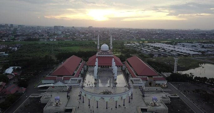 Reveal drone shot of the great Mosque of Central Java (MAJT) in suset time. Th sun is orange and the weather is cloudy.