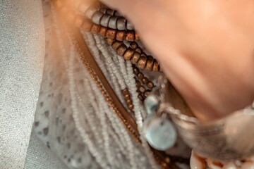 Close up of beautiful tribal boho style woman hands with lots of accessories. Boho style for fashionable look on resort. Middle aged well looking woman in white dress and boho style braclets.