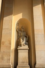 View of marble statue of athena inside Brandenburg gate arch wall holding spear and wearing helmet in summer.