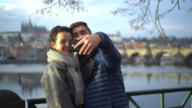Couple making selfie in front of Charles Bridge in Prague and kissing, closeup day view