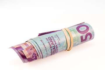 Roll of New Zealand banknotes secured by a rubber band and isolated against a white background.