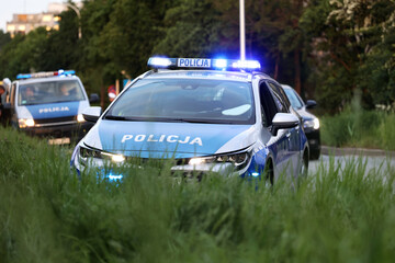 Samochód polskiej policji drogowej na sygnałach w mieście alarmowo.  - obrazy, fototapety, plakaty