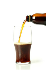 Kvass pouring from bottle to glass, isolated on white background