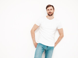 Portrait of handsome confident stylish hipster lambersexual model. Sexy man dressed in T-shirt and jeans. Fashion male isolated on white wall in studio