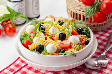 Italian cold pasta salad or Pasta fredda alla caprese. Fusilli, tomato, mozzarella, olive, arugula....
