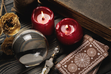 Tarot cards, crystal ball and magic books on the old wooden table close up background.