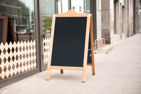 Blank wooden sandwich board near cafe outdoors. Mockup for design
