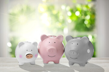 Group piggy banks on white wooden table near window in room