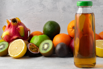 Various fruits and freshly squeezed fruits juice in bottle on gray background