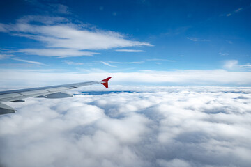 Aircraft wing above beautiful clouds and blue sky
