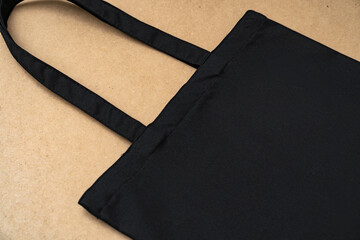 Black textile shopping bag on beige background flat lay