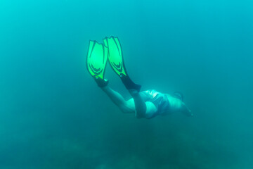 A freediver dives into the depths with his fins