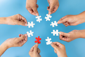 people helping in assembling puzzle, cooperation in decision making, team support in solving problems and corporate group teamwork concept, close up view of hands connecting pieces