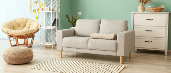 Interior of modern living room with comfortable couch, armchair and chest of drawers