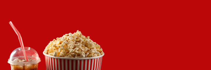 Tasty popcorn and cold cola on red background with space for text