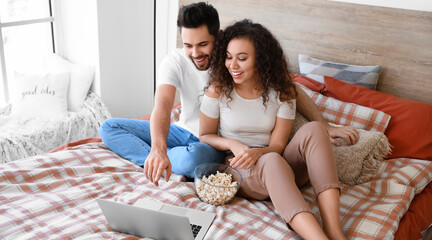 Fototapeta Happy young couple watching movie in bedroom obraz