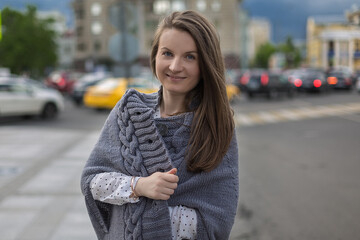 Fototapeta premium Street portrait of a young woman dressed in a gray cardigan.