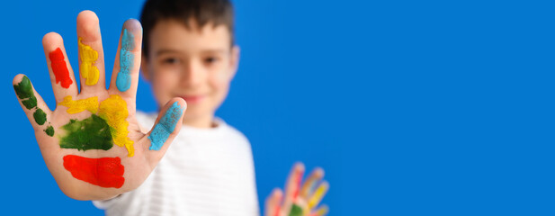 Little boy with hand in paint on color background, closeup