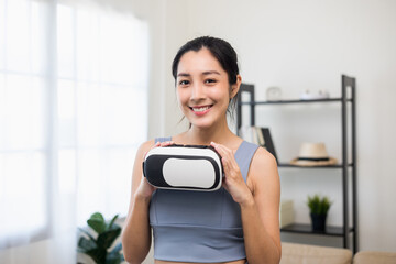 Young asian sport woman holding vr glasses wearing sportswear workout with virtual simulated world. Into the  future digital cyber universe. Future technology Training virtual sport at home
