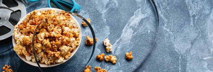 Popcorn in bowl with 3D glasses and film reel on blue background with space for text