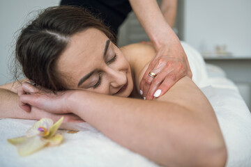 Obraz na płótnie Canvas close up of female masseur doing curative healing massage on female client shoulder and back in spa
