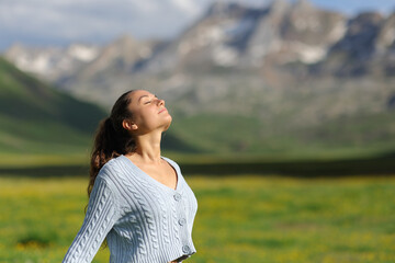 Casual woman breathing fresh air in a green mountain