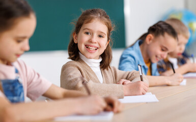 Cheerful girl solving test with classmates