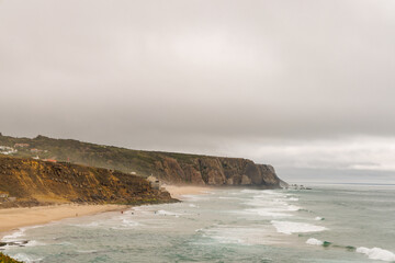 Rocky formations and fog amongst the waves on the coast of Portugal