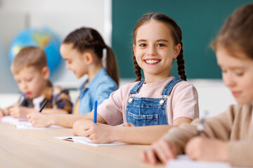 Cheerful girl solving test with classmates