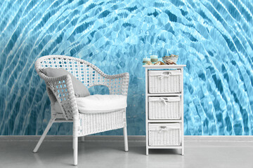 Armchair and shelf unit near wall with print of clear blue water
