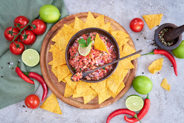 freshly made salsa dip sauce with nacho chips on wooden board