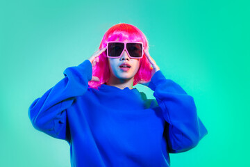 Young asian woman in blue sweatshirt pink short hair punk style wearing sunglasses posing dancing...