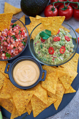 freshly made salsa and guacamole dip sauce with nacho chips on stone serving board