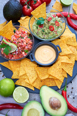 freshly made salsa and guacamole dip sauce with nacho chips on stone serving board